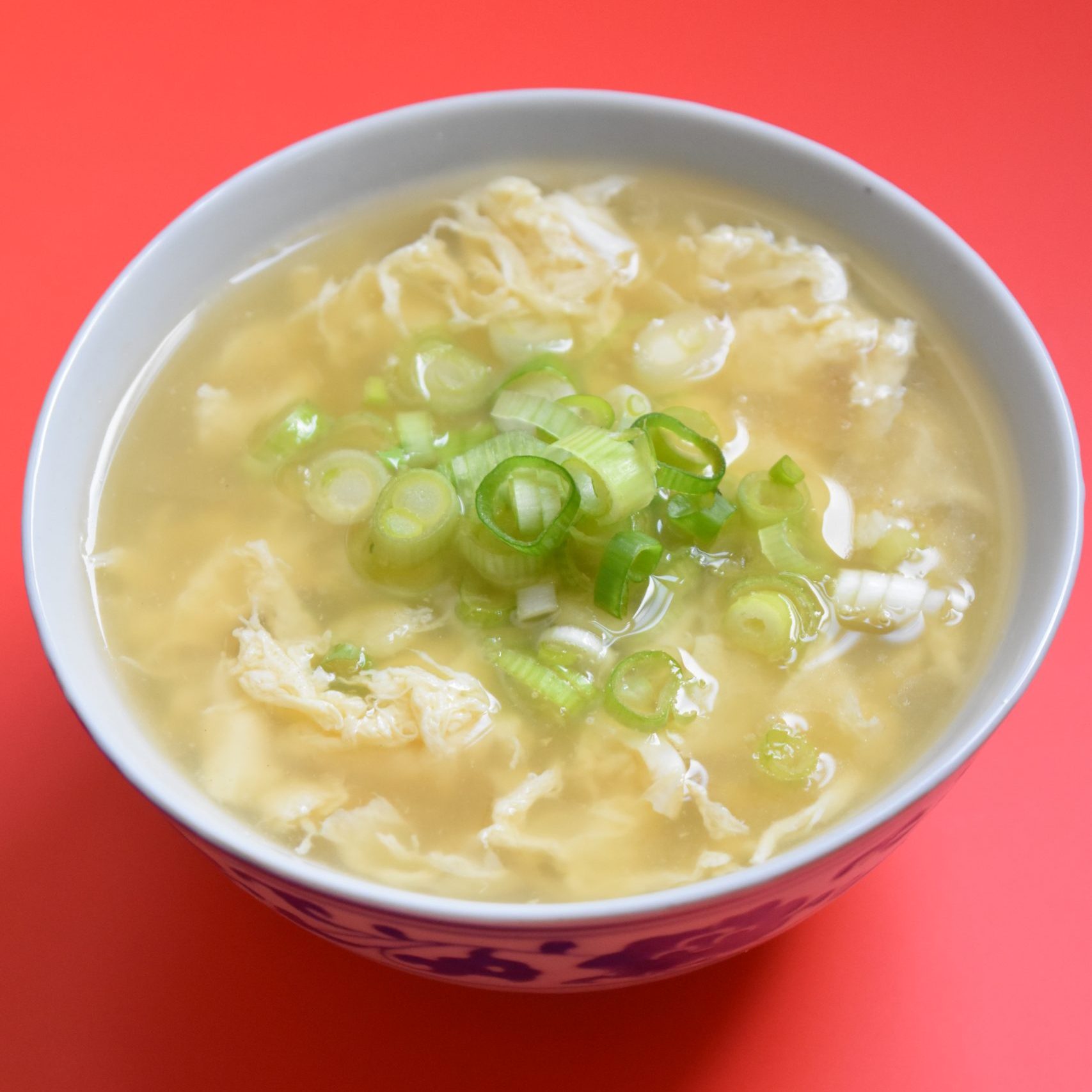 A blue and white bowl with fluffy strings of eggs and green onion.