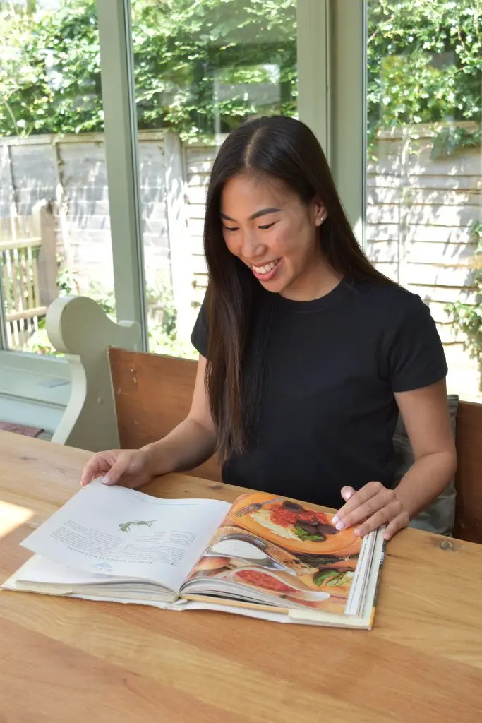Dee in a black t-shirt reading a cook book
