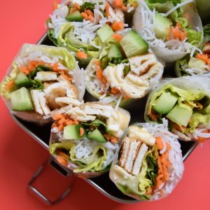 Vietnamese egg cold rolls with peanut sauce in silver lunchbox on red background