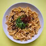 A plate of chilli garlic noodles on yellow background